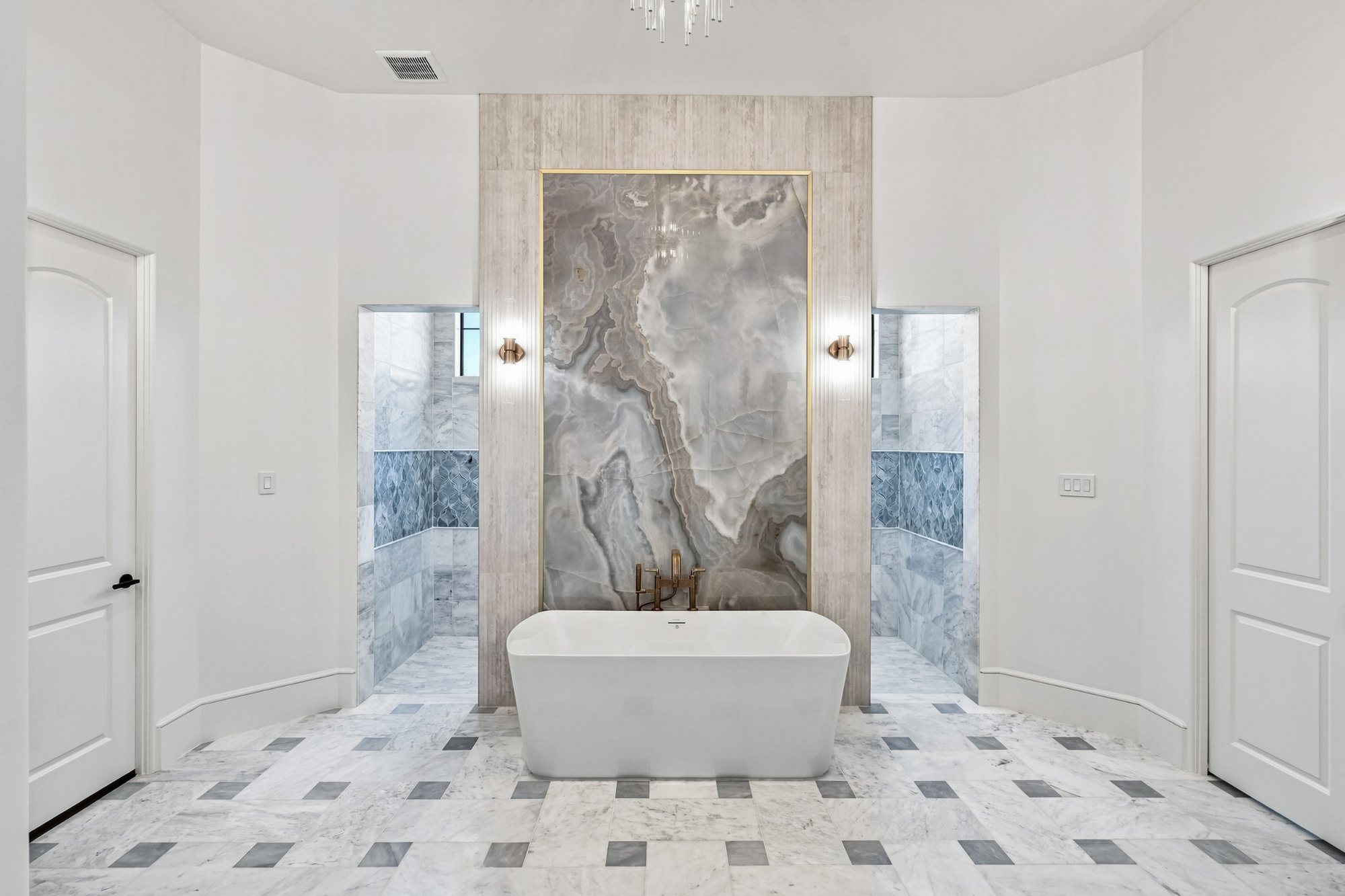 Primary bath with a book-matched stone wall and freestanding tub
